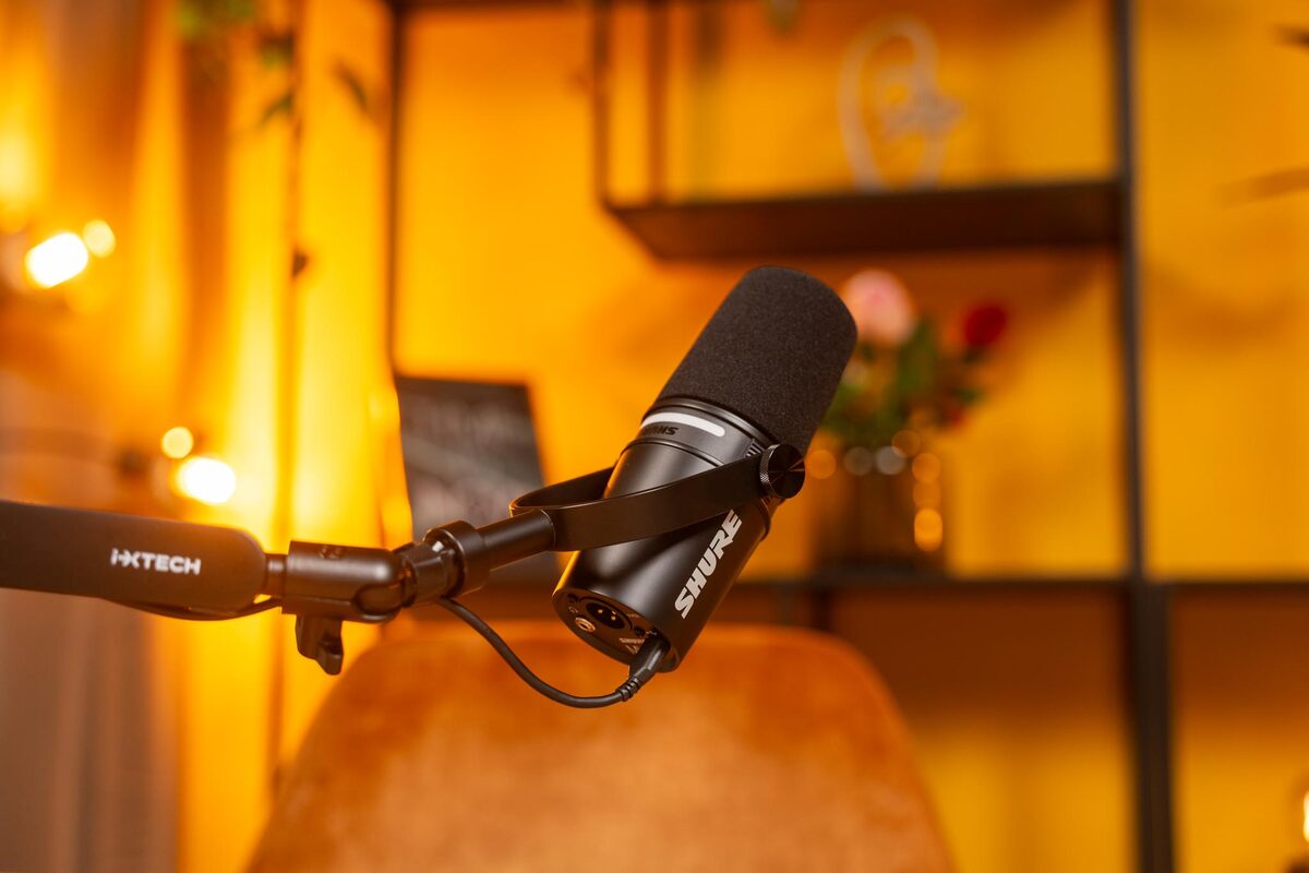 Shure-Mikrofon am Galgenarm im warm beleuchteten Podcast-Studio