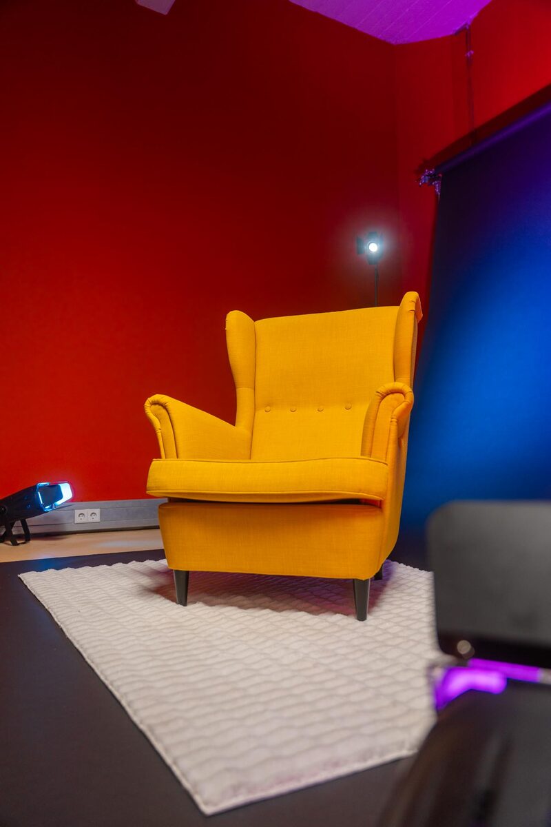 Gelber Sessel vor farbigem Studio-Backdrop mit Beleuchtung